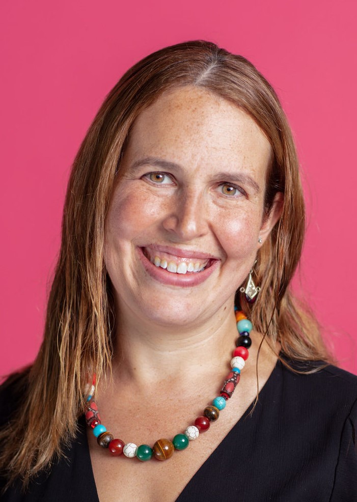 A smiling woman wearing a colorful necklace.